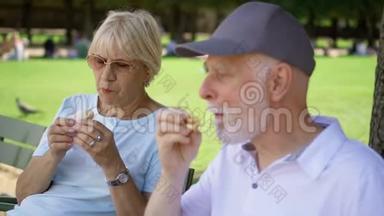 <strong>饥饿</strong>的老年人在公园里吃三明治。 游客在公共公园享用午餐，享受夏日阳光